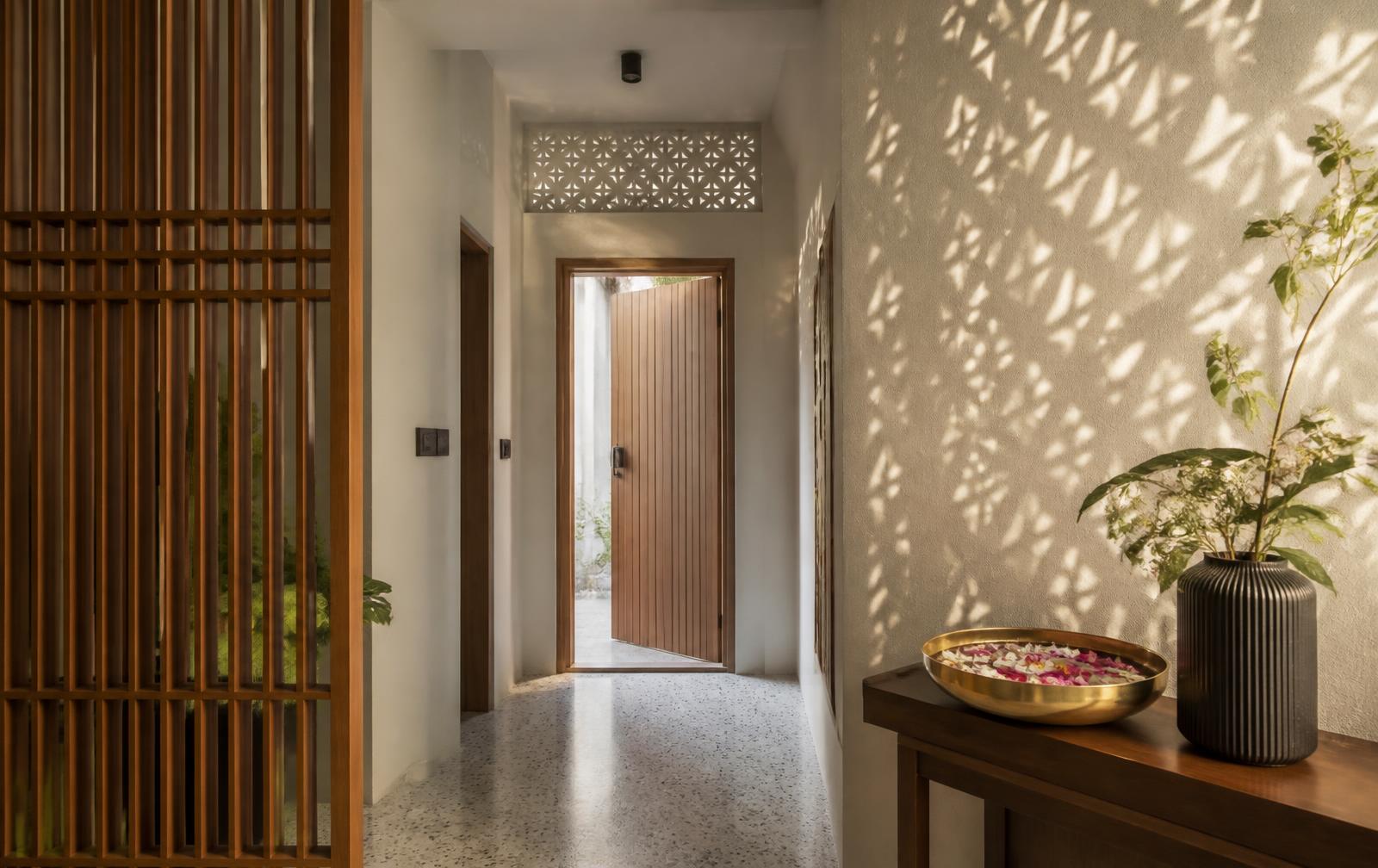 Entrance foyer with a teak screen, terrazzo floor and brass urli