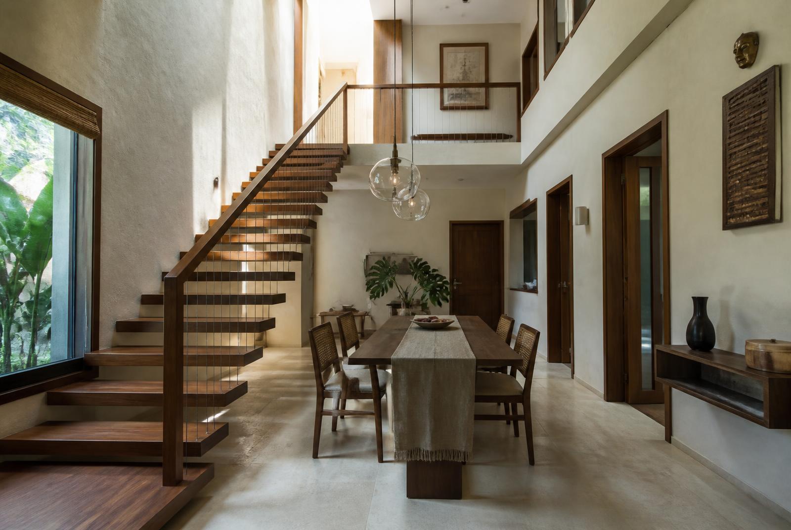 Floating timber staircase beside the dining table, double-height volume